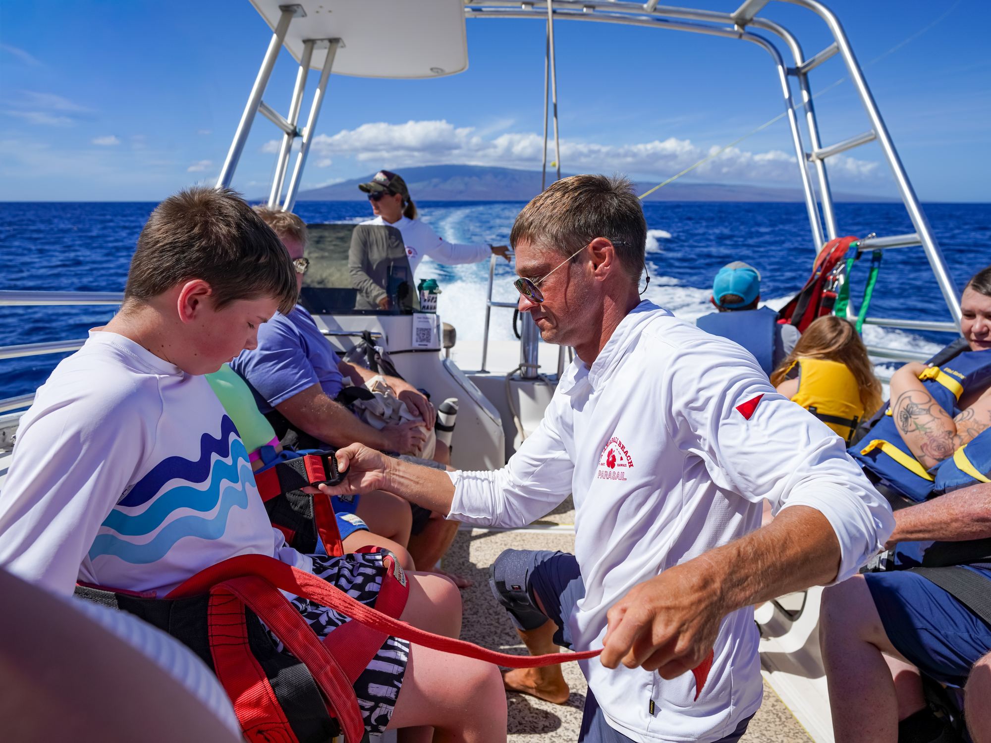 A young flyer being fitted into a parasail harness on the boat deck